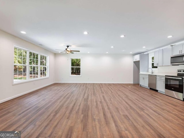 kitchen with appliances with stainless steel finishes, sink, ceiling fan, and light hardwood / wood-style floors