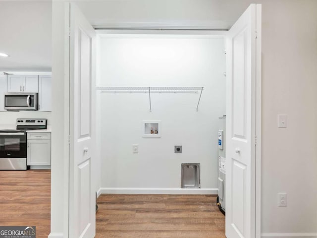 washroom with water heater, hookup for an electric dryer, washer hookup, and hardwood / wood-style flooring