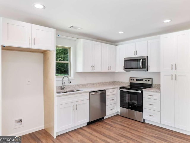 kitchen with white cabinetry, sink, stainless steel appliances, and light hardwood / wood-style floors