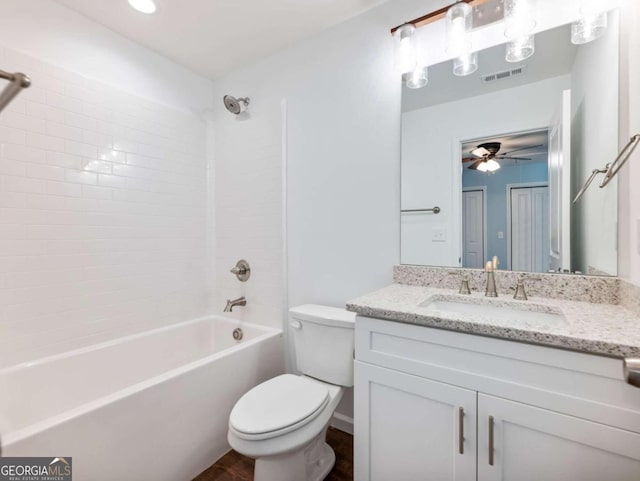 full bathroom with tiled shower / bath, vanity, toilet, and ceiling fan