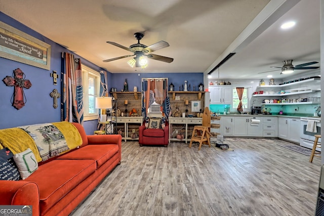 living room with ceiling fan, sink, light wood-type flooring, and plenty of natural light