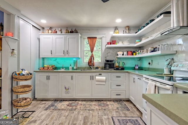 kitchen featuring light hardwood / wood-style flooring, white cabinets, electric stove, wall chimney exhaust hood, and sink