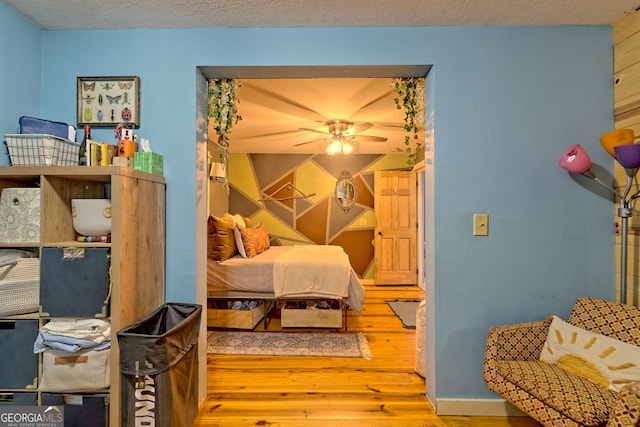 bedroom with light hardwood / wood-style flooring, a textured ceiling, and ceiling fan