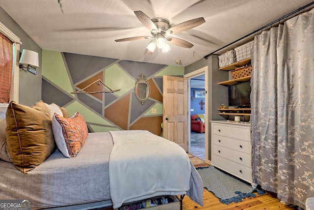 bedroom featuring light hardwood / wood-style flooring, a textured ceiling, and ceiling fan