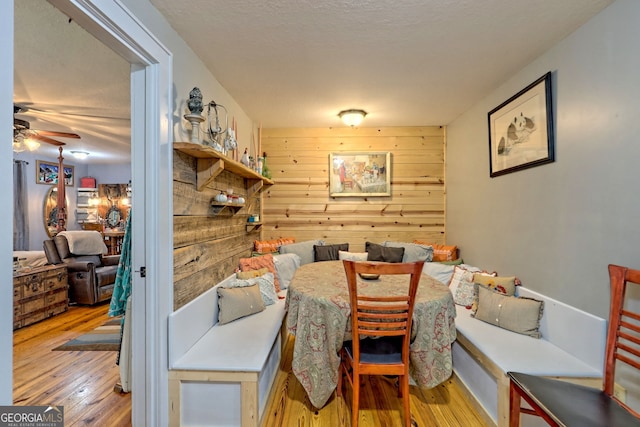 dining room featuring wood walls, ceiling fan, and light hardwood / wood-style floors