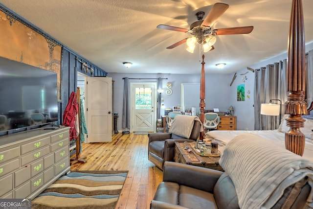 living room featuring a textured ceiling, ceiling fan, and light wood-type flooring