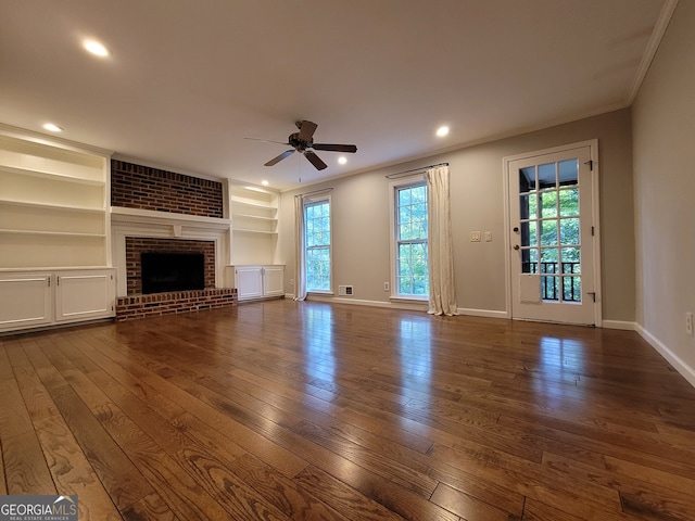 unfurnished living room with ceiling fan, hardwood / wood-style flooring, a fireplace, built in shelves, and ornamental molding