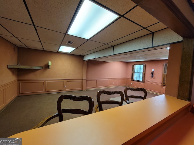 dining space featuring carpet flooring and a drop ceiling