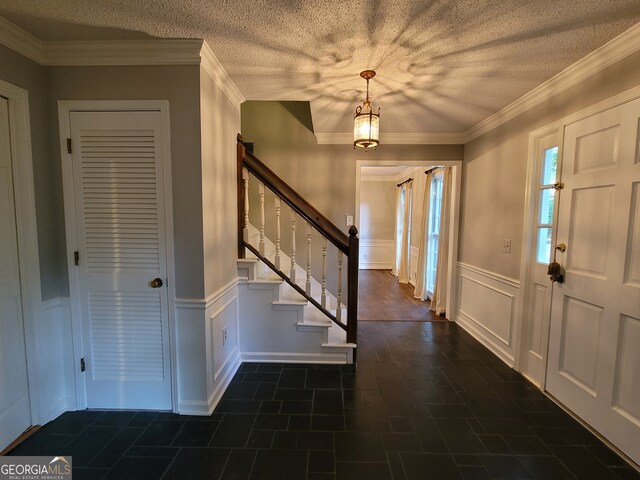 entrance foyer featuring crown molding, dark tile patterned floors, and a textured ceiling