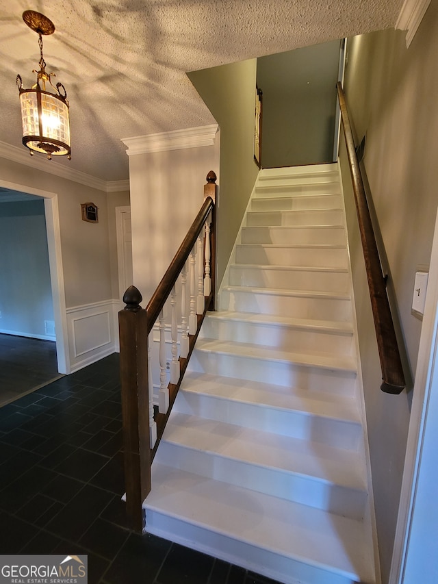 stairs with crown molding, dark tile patterned floors, and a textured ceiling