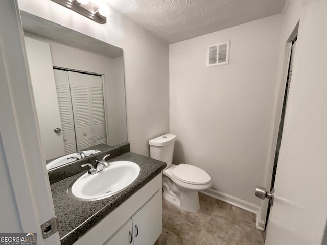 bathroom with vanity, toilet, a textured ceiling, and tile patterned flooring