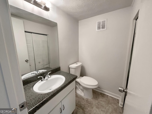 bathroom featuring vanity, a textured ceiling, and toilet