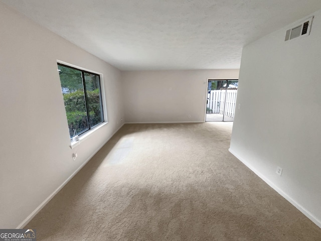 carpeted empty room with a textured ceiling