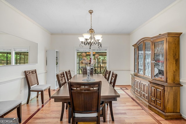 dining space featuring an inviting chandelier, crown molding, light hardwood / wood-style floors, and a textured ceiling