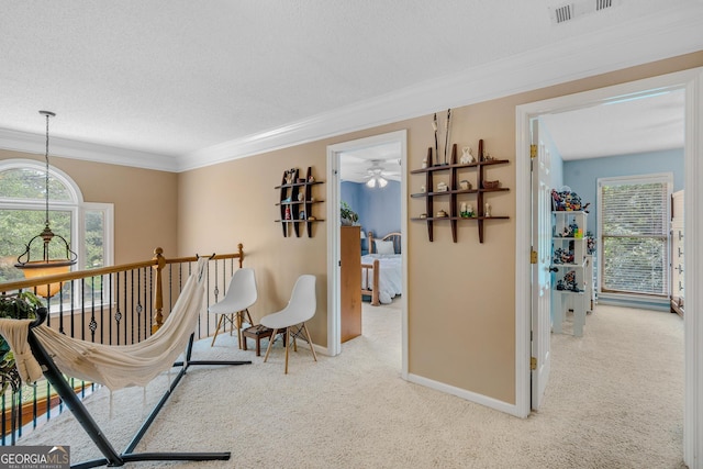 hall with light colored carpet, ornamental molding, and a textured ceiling