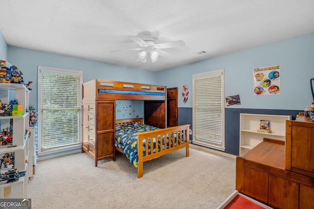 carpeted bedroom with ceiling fan and a textured ceiling