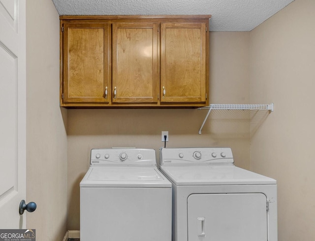 clothes washing area with cabinets, washing machine and dryer, and a textured ceiling