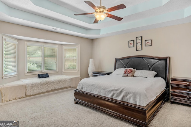 bedroom featuring a raised ceiling, carpet floors, and ceiling fan