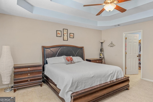 carpeted bedroom with ceiling fan and a raised ceiling