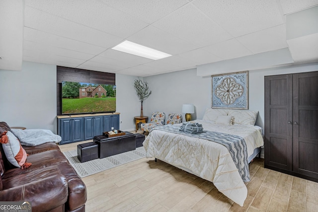 bedroom with a drop ceiling and light hardwood / wood-style flooring