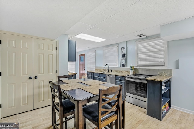 kitchen featuring a drop ceiling, sink, light wood-type flooring, and appliances with stainless steel finishes