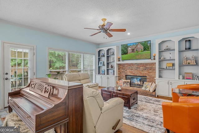 living room featuring ornamental molding, a brick fireplace, and a textured ceiling