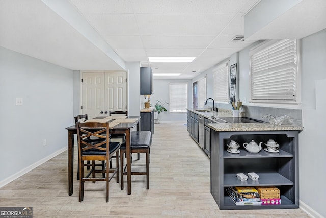 dining area with a drop ceiling, sink, and light wood-type flooring