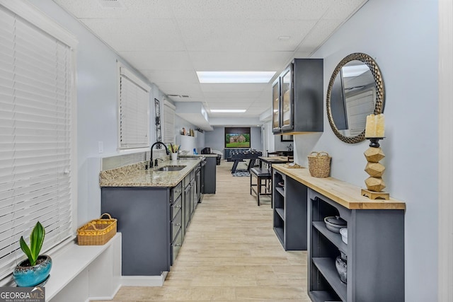 kitchen featuring a drop ceiling, sink, butcher block countertops, and light wood-type flooring