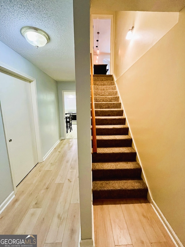 staircase with hardwood / wood-style flooring and a textured ceiling