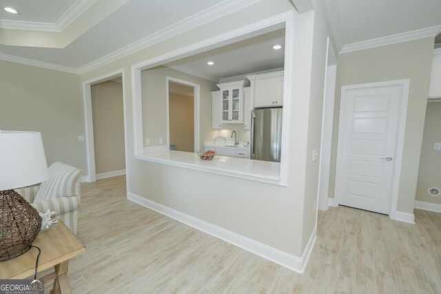 living room with ceiling fan, a raised ceiling, ornamental molding, and light wood-type flooring