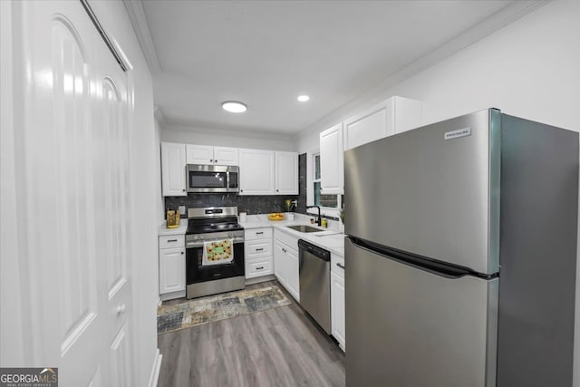 kitchen with white cabinets, appliances with stainless steel finishes, light hardwood / wood-style floors, and sink