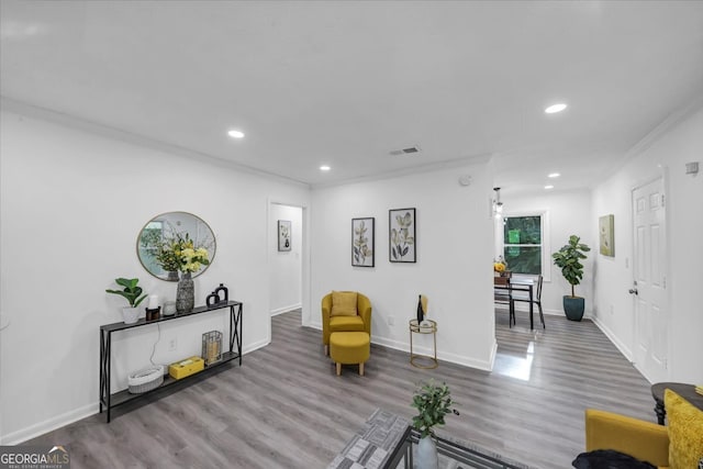 living room with hardwood / wood-style flooring, ornamental molding, and a healthy amount of sunlight