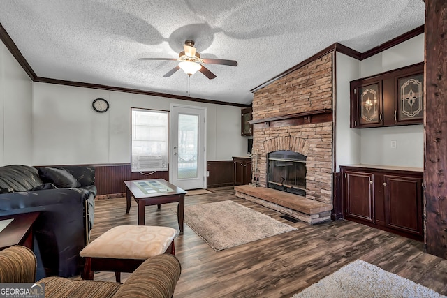 living room with ceiling fan, a brick fireplace, ornamental molding, and dark wood-type flooring