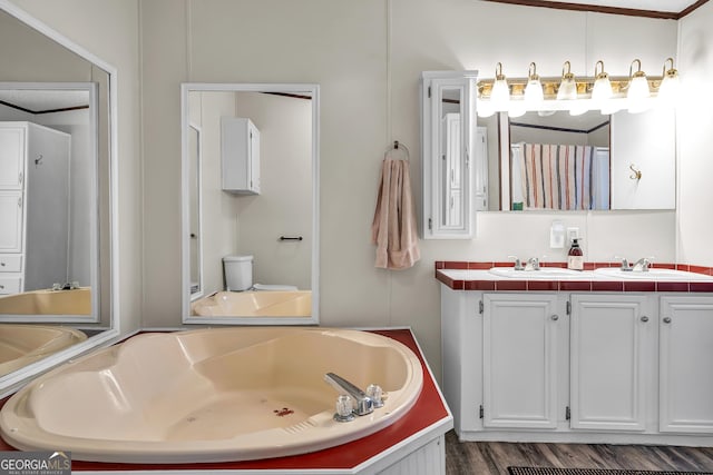 bathroom featuring hardwood / wood-style flooring, a washtub, vanity, and ornamental molding