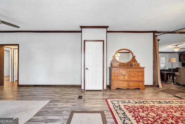 interior space featuring ceiling fan, ornamental molding, a textured ceiling, and wood-type flooring