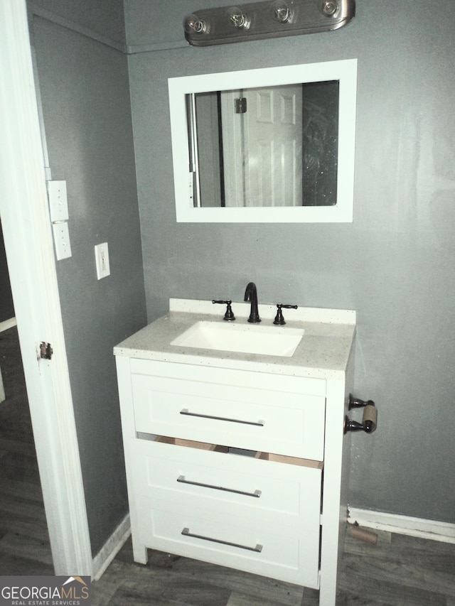 bathroom with baseboards, wood finished floors, and vanity