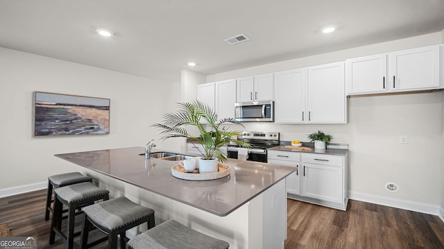 kitchen with stainless steel appliances, an island with sink, and white cabinets