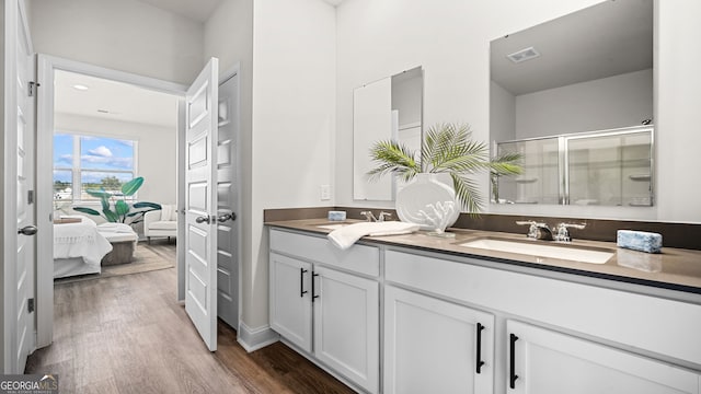 bathroom featuring wood-type flooring, vanity, and a shower with shower door