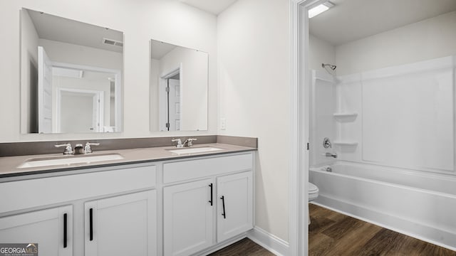 full bathroom with hardwood / wood-style flooring, washtub / shower combination, vanity, and toilet