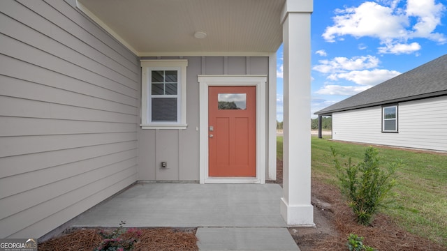 view of exterior entry featuring a lawn