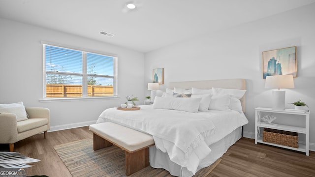 bedroom featuring wood finished floors, visible vents, and baseboards