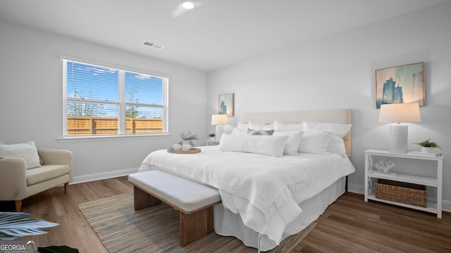 bedroom featuring visible vents, baseboards, and wood finished floors