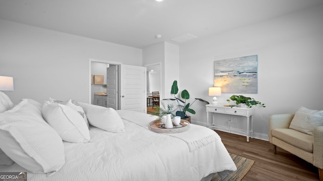 bedroom featuring baseboards, wood finished floors, and ensuite bathroom