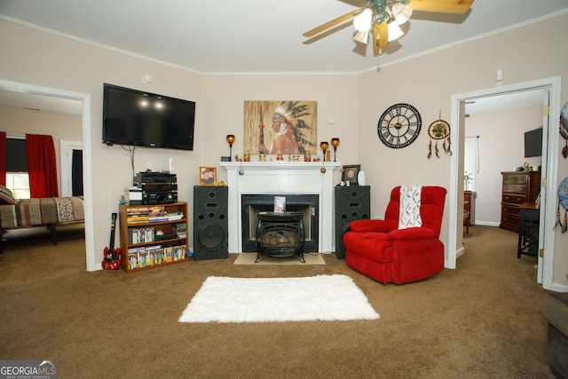 living room featuring a wood stove, crown molding, carpet floors, and ceiling fan