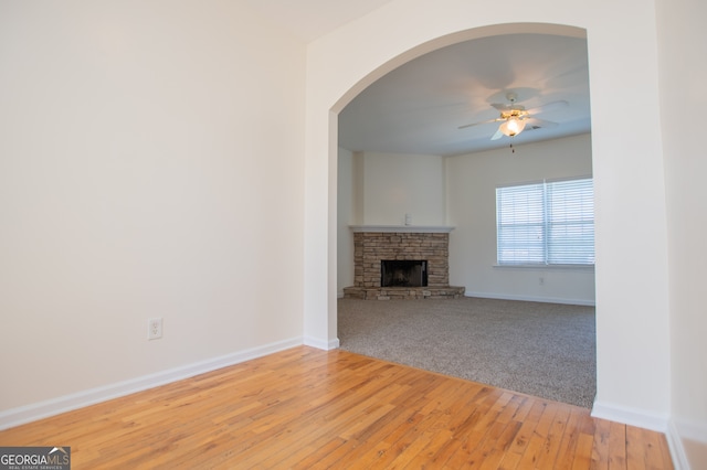 unfurnished living room featuring ceiling fan, a fireplace, and light hardwood / wood-style flooring