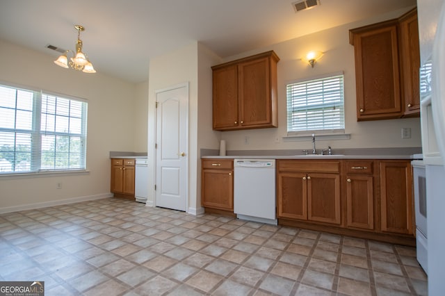 kitchen with a notable chandelier, sink, white appliances, and light tile patterned floors