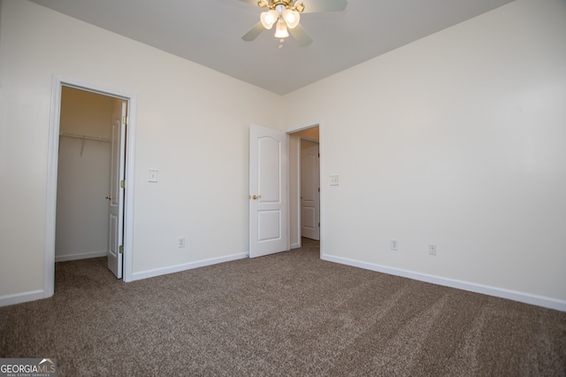 unfurnished bedroom featuring a walk in closet, carpet flooring, a closet, and ceiling fan