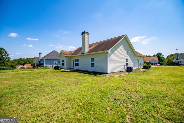 back of property with central air condition unit and a yard