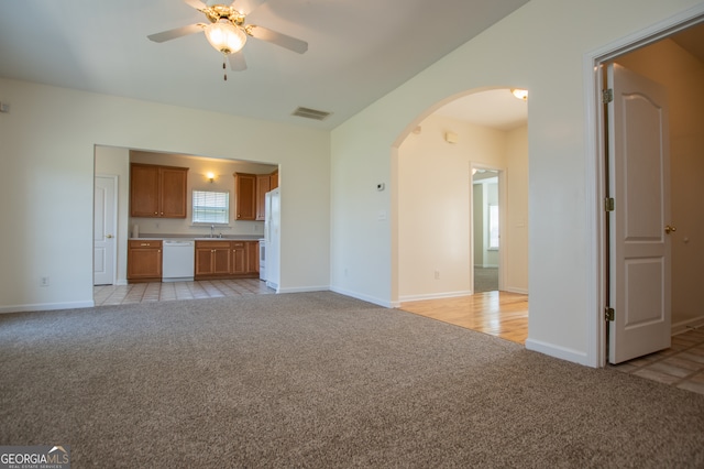 unfurnished living room featuring light carpet, sink, and ceiling fan