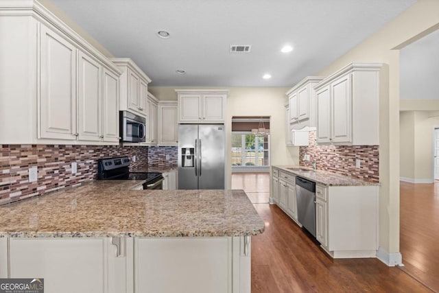 kitchen with appliances with stainless steel finishes, dark hardwood / wood-style floors, kitchen peninsula, and white cabinets